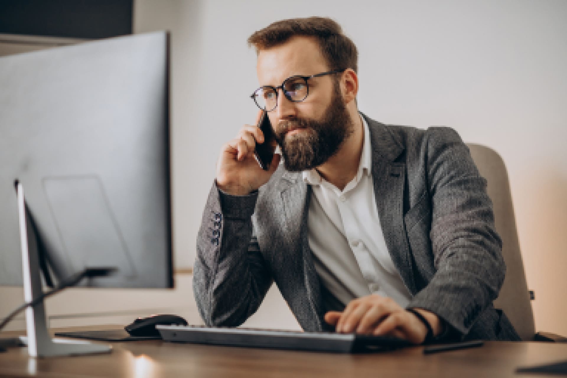 [:pt]young-business-man-talking-phone-working-computer (1)-low[:]